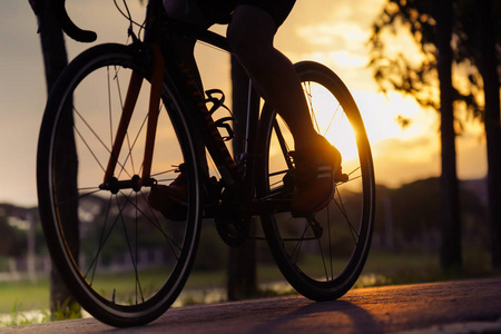 自行车在夏天日落在路在城市公园。夏季模糊光上循环特写轮