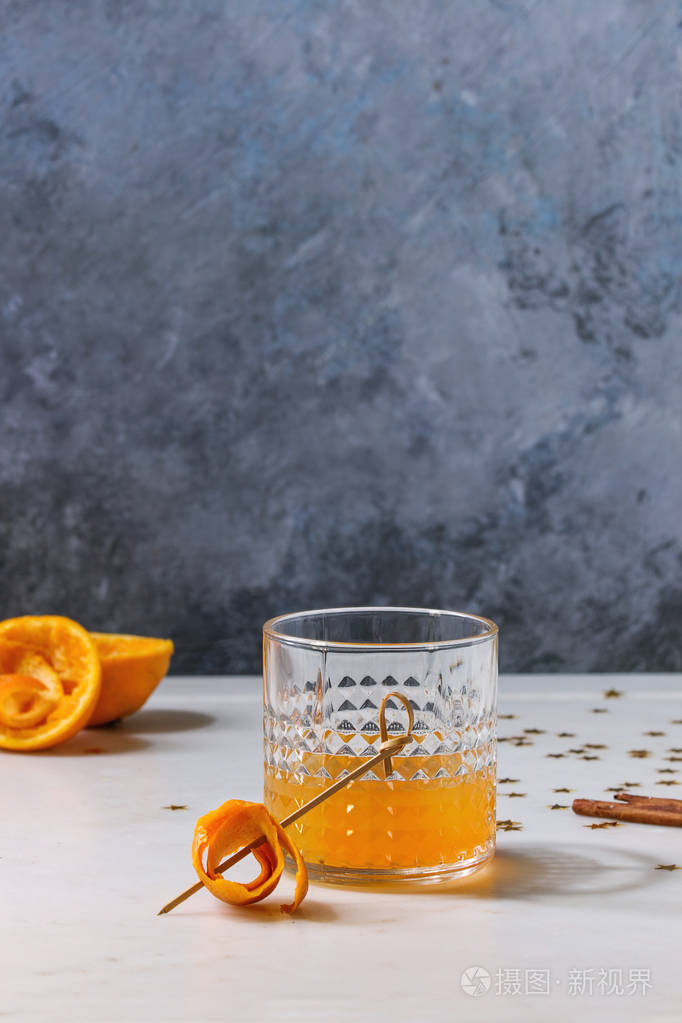 杯苏格兰威士忌橙汁酒精鸡尾酒与盘旋橙色果皮在串和肉桂棍子站立在