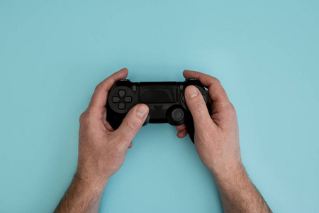 男子手持电子游戏游戏控制器手上柔和的蓝色背景