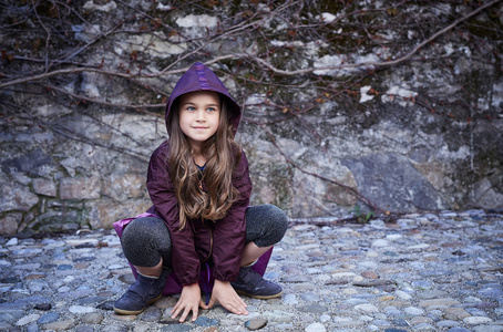 在罩一个女孩坐在一块灰色的岩石上