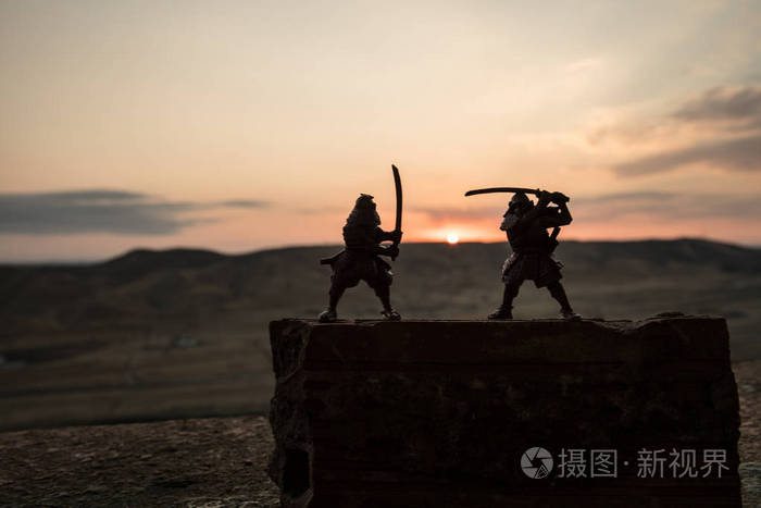 两个武士的剪影在决斗.图片与两个武士和日落的天空.选择性聚焦