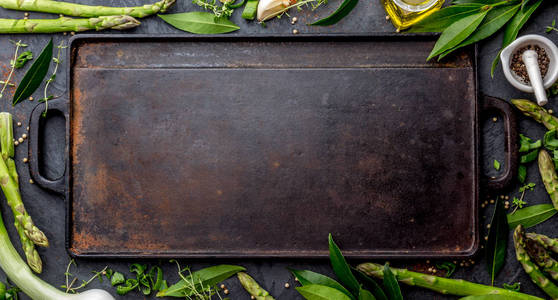食物背景与文本的自由空间。香草, 橄榄油, 香料周围的铸铁煎板。顶部视图