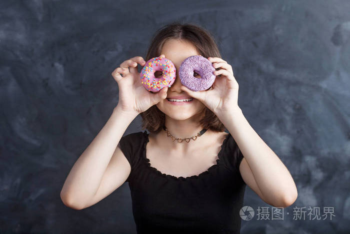 有吸引力的女孩拿着新鲜的甜甜圈和甜的东西乐趣.好心情, 饮食观念