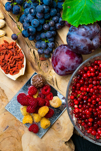 富含白藜芦醇葡萄李子枸杞花生蔓越莓raspberrys 巧克力黑色木质背景的食物健康早餐的食品新鲜浆果水果坚