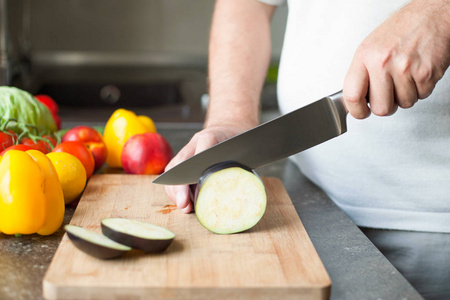 一位专业厨师用陶瓷刀迅速将茄子切在木板上。特写