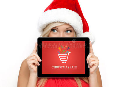 戴着红色圣诞帽的女孩拿着屏幕上有圣诞特卖的平板电脑过年