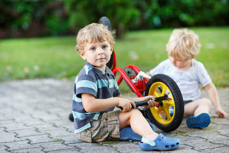 两个小男孩，兄弟姐妹，在户外修理自行车。