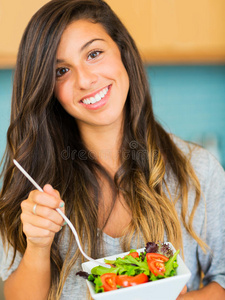 美丽的年轻女子吃着一碗健康的有机沙拉