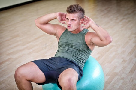 有魅力的年轻人在健身房用健身球