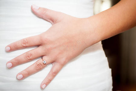 婚纱上戴订婚戒指的女人的手