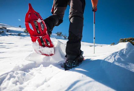 男子在穿雪鞋与徒步竿。在雪地上行走的设备关闭了。在冬天的山上旅行。旅行鞋。男士腿
