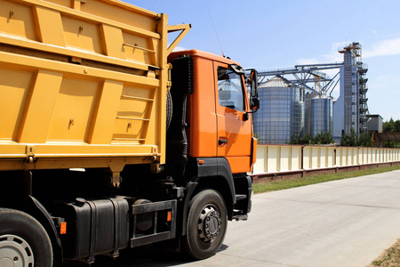 橙色卡车在粮食储藏领域在晴朗的天气收获照片