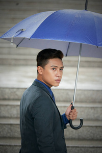 亚洲商人带蓝色雨伞户外雨天天气