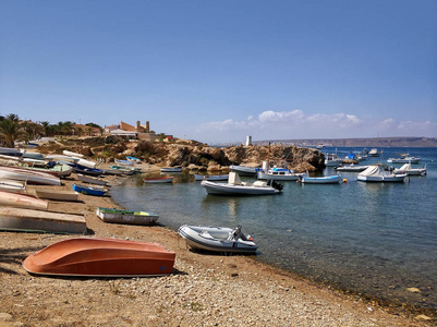 在 Tabarca 岛的空卵石海滩捕鱼机动艇。夏季度假游客的著名旅游胜地。宁静清澈的地中海湾, 蓝天。西班牙的圣诞老人
