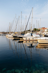 小船和船在码头在普拉，克罗地亚在日落时。桅杆，反映在海