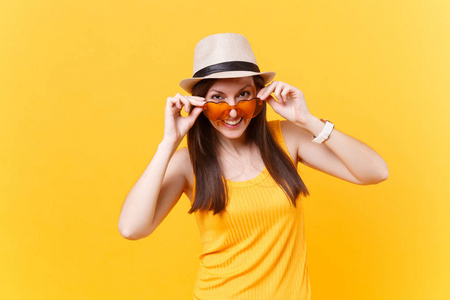 年轻女子的画像在稻草夏天的帽子, 把手放在橙色的心眼镜, 复制空间, 在黄色背景上隔离。人真挚的情感, 生活方式的观念。广告专区