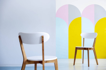 两个白色的椅子在明亮的室内部互相面对与柔和的装饰。真实照片, 前景模糊