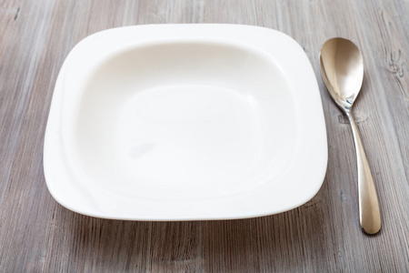 白色的方形碗和勺子上灰色的棕色的桌子