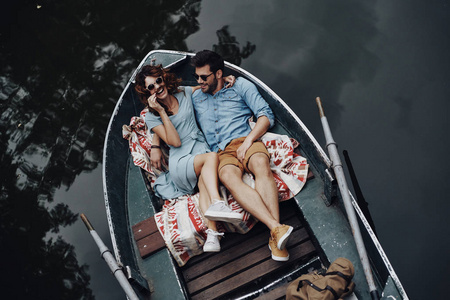 美丽的年轻夫妇拥抱和微笑, 而躺在船上的顶部视图