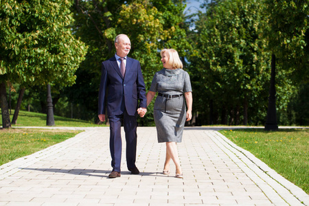 愉快的前辈夫妇在夏天散步在公园