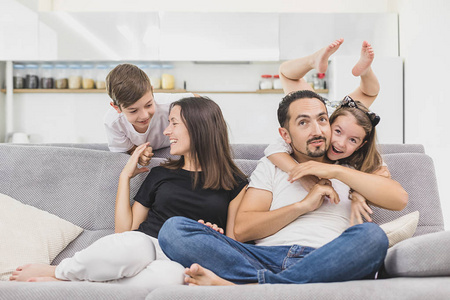 的情侣笑着玩游戏与小活泼的孩子在家里的客厅里, 家庭滑稽活动照片
