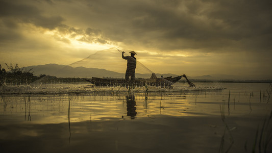 Bangpra 湖在行动时在阳光的早晨，泰国，选择重点钓鱼的渔夫