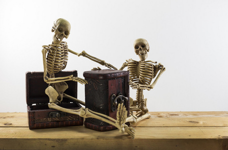 坐在宝箱和旧的木地板上的骷髅海盗照片