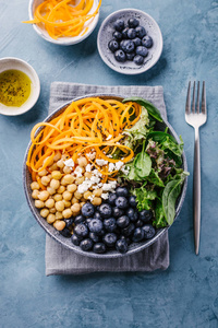 蓝桌上有南瓜黑莓鹰嘴豆和菠菜的佛碗沙拉。健康干净的饮食排毒概念。顶部视图
