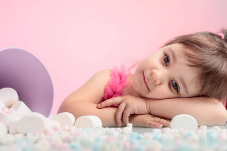 一个可爱的小女孩的肖像与棉花糖, 孤立的粉红色背景。表情表情。复制文本的空间