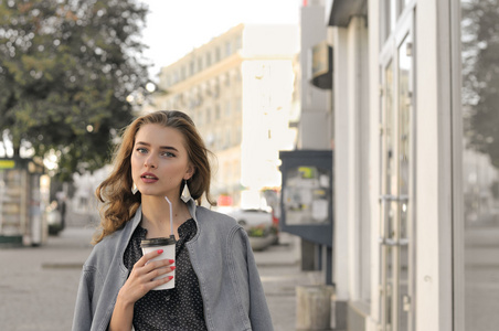 女孩走在人行道上，喝着咖啡