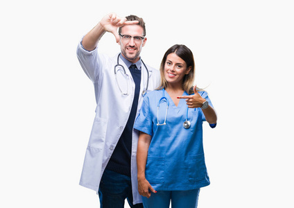 年轻夫妇的医生和外科医生在孤立的背景微笑制作框架与手和手指愉快的脸。创意与摄影理念