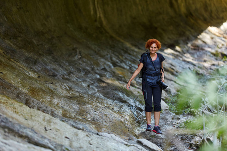 中年女性徒步旅行者白天走路。妇女与背包徒步旅行在山的足迹