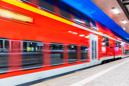 创意抽象铁路旅游与铁路运输产业理念 现代红色高速电力客运专线列车在夜间照明车站平台上的运动模糊效果