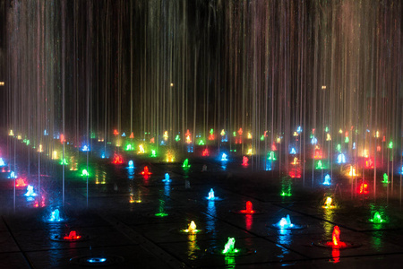 在夜间照明的彩色喷泉。一个美妙的喷泉。背景