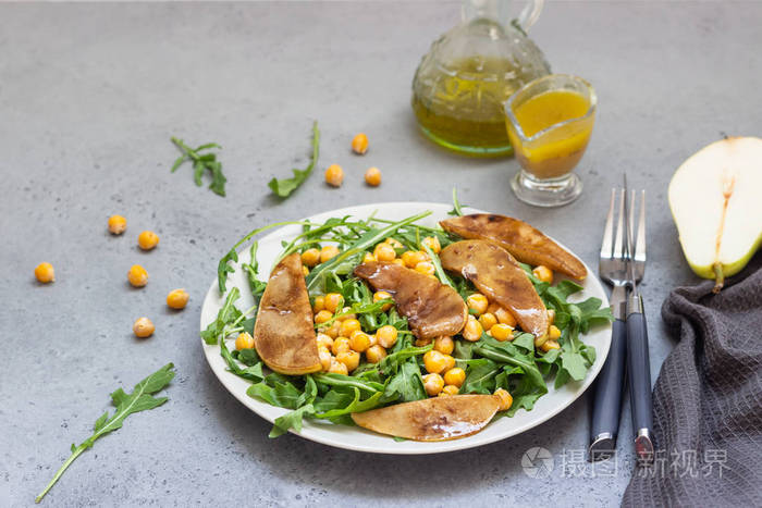 健康蔬菜沙拉与辣鹰嘴豆, 芝麻菜和梨在天然石材背景。美味均衡的食物概念。素食
