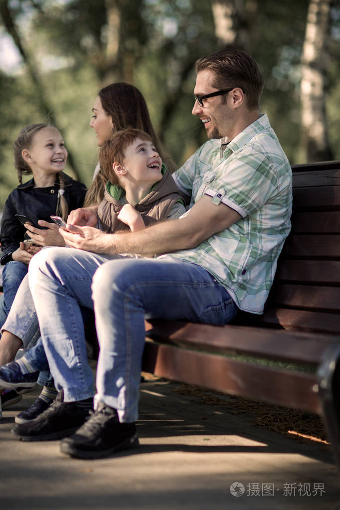 父母和孩子们坐在公园的长凳上放松