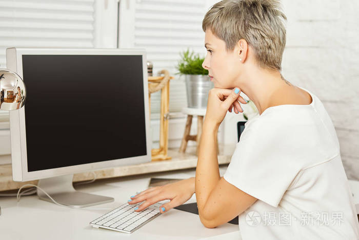 美丽的商业妇女穿着白色礼服坐在办公桌上, 在家里的办公室电脑工作