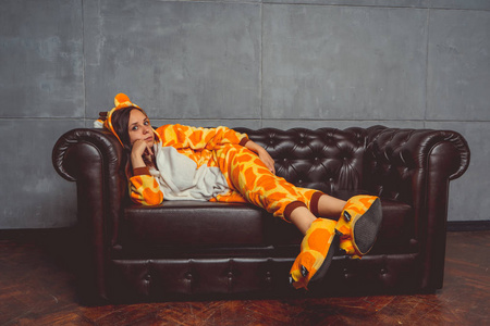 在长颈鹿的形式睡衣。在背景真皮沙发上的一个学生的情感肖像。穿着西装的疯子和滑稽的男人