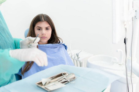 年轻女性病人坐在牙医办公室时看起来很害怕