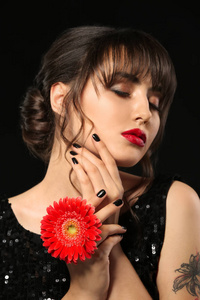 美丽的年轻女子与专业的指甲和花黑色背景