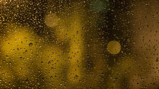 窗户玻璃上的雨滴。晚上的时间。窗口中的视图