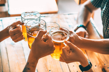 酒吧举杯朋友们在酒吧里喝着淡啤酒举杯祝酒.照片