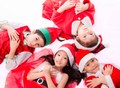 快乐的孩子，在躺在地板上的圣诞服装集团享受孤独的白色背景