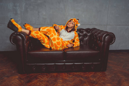 在长颈鹿的形式睡衣。在背景真皮沙发上的一个学生的情感肖像。穿着西装的疯子和滑稽的男人