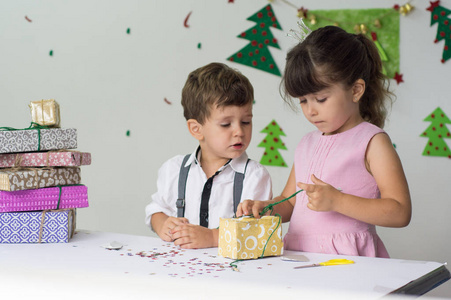 可爱的快乐兴奋的孩子, 男孩和女孩打开圣诞礼物盒在美丽的房间。姐姐和哥哥在装饰树附近赠送圣诞礼物。家庭假期