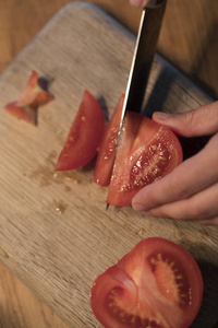 在切割板上切西红柿的人