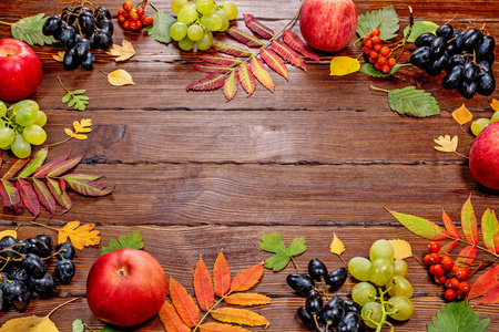 在木质背景下的苹果和葡萄的秋天叶子