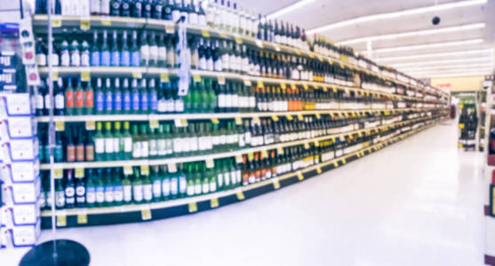 全景视图模糊的葡萄酒过道与价格标签在美国德克萨斯州的杂货店。弥散在超市货架上排红白葡萄酒酒瓶。酒精饮料文摘背景