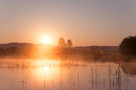 春天倒映在湖面上的薄雾金色日出
