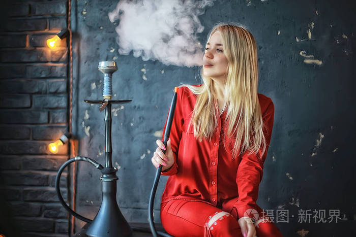 有吸引力的年轻金发女子在红色衣服吸烟水烟